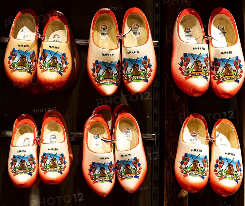 Colourfully painted traditional Dutch wooden shoes hanging on a wooden wall