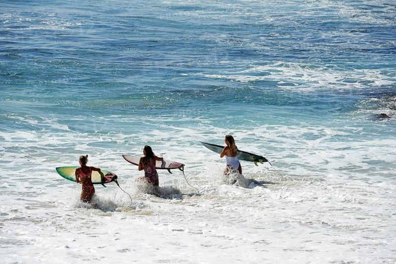 Three tourists with surfboards at Jimbaran Beach