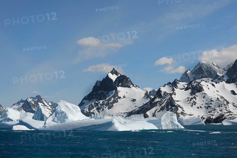 Floating icebergs off mountain peaks with snow