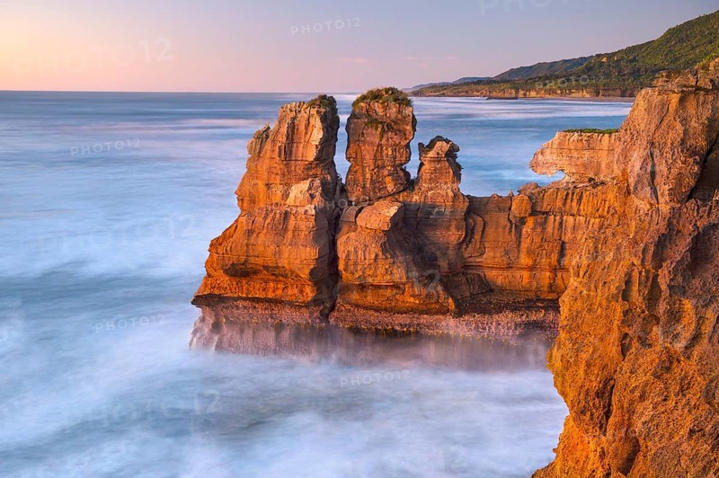 Rock formations on the coast of Paparoa National Park in red evening sun, Punakaiki