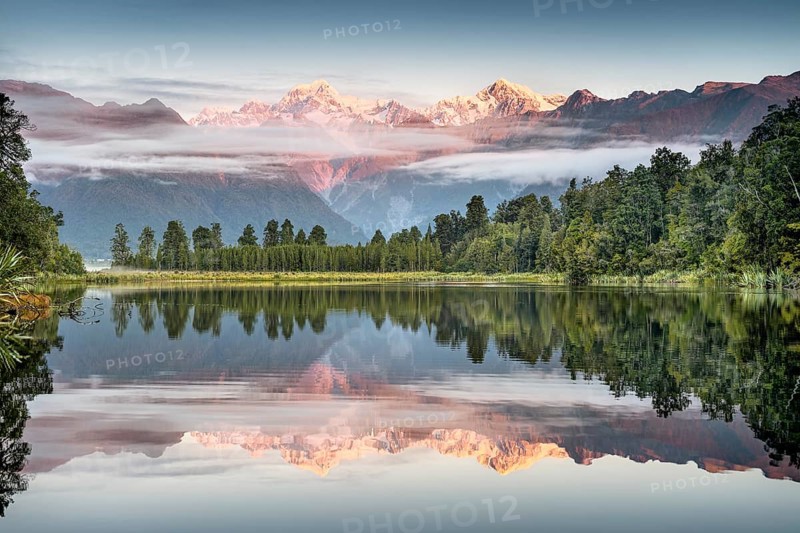 Veil clouds in front of Mount Cook and Mount Tasman are reflected in Lake Matheson in the evening light, Westland National Park