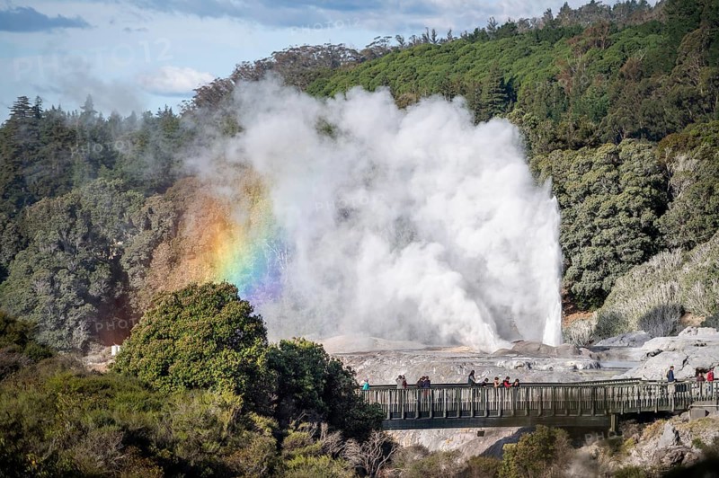 Tourists on bridge, view of erupting Pohutu Geyser with rainbow