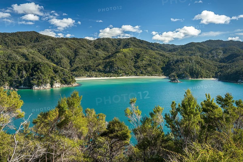 Green sea with yellow sandy beach, tropical hills in the back