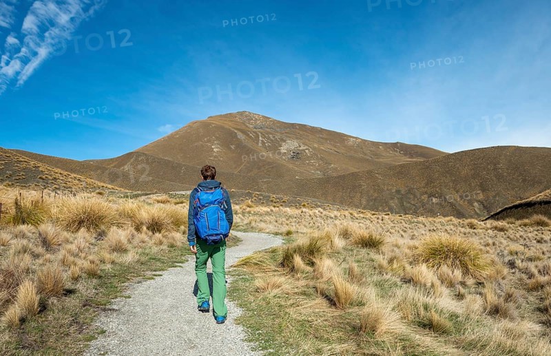 Hiker on hiking trail in barren mountain landscape, Lindis Pass