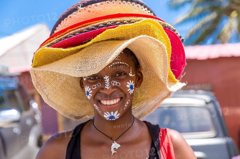 Local saleswoman with traditional face painting sells sun hats, Diego Suarez