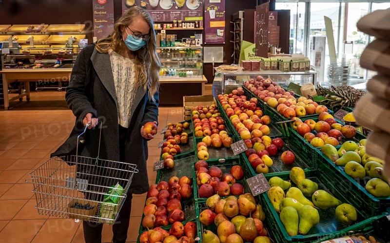 Young woman shopping in a supermarket with face mask, corona crisis