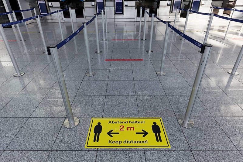 Sign with distance rule in front of the deserted baggage check, flight ban due to corona pandemic