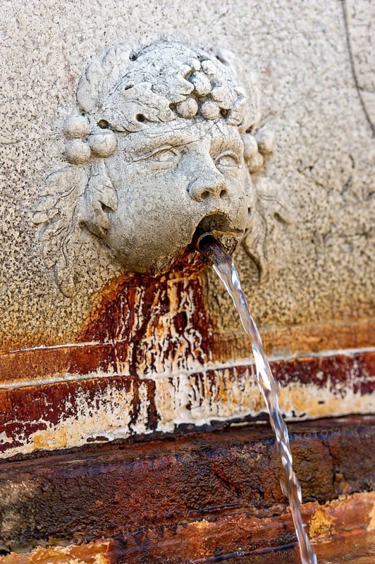 Putto, gargoyle with rusty red discoloration at the Neptune Fountain