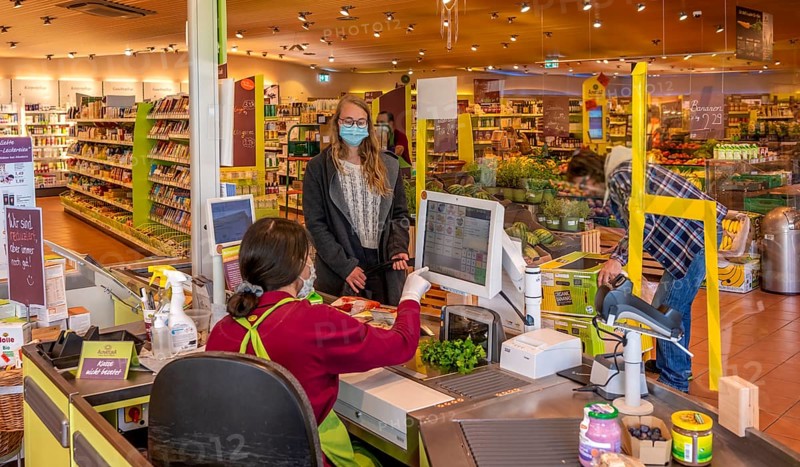 Young woman shopping in a supermarket with face mask, corona crisis