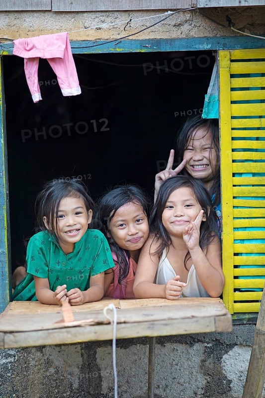 Happy children looking out of the window of their house