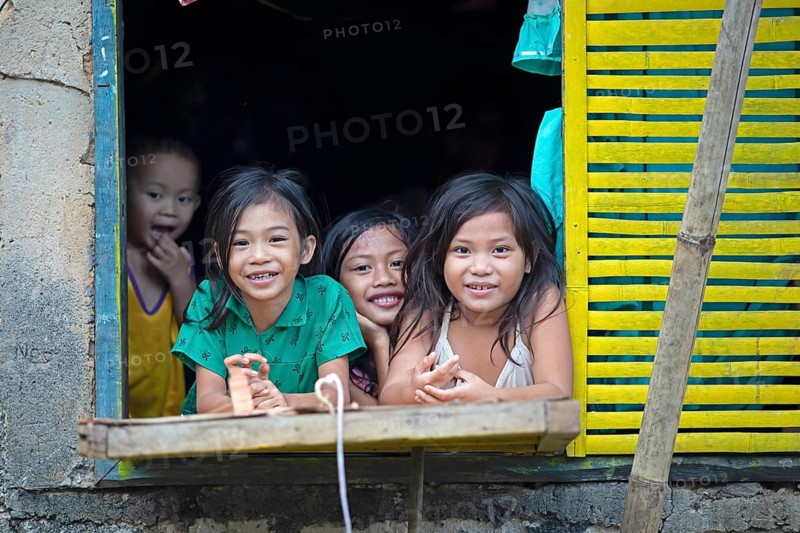 Happy children looking out of the window of their house