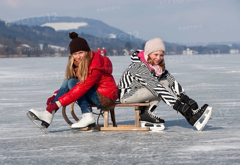 Young happy girls ice skating at a lake
