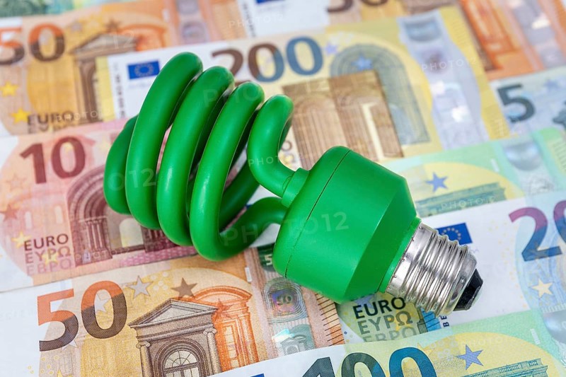 Green energy-saving lamp on euro banknotes