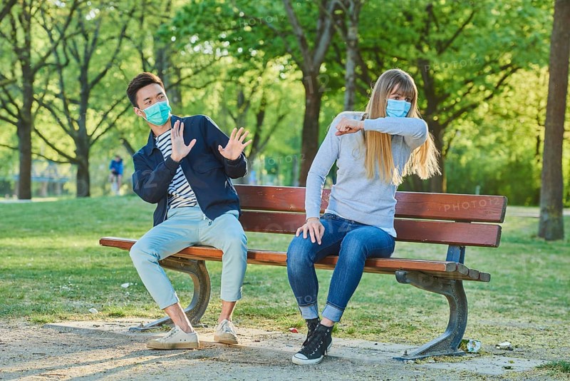 Man and woman wearing a face mask on a park bench in a municipal park
