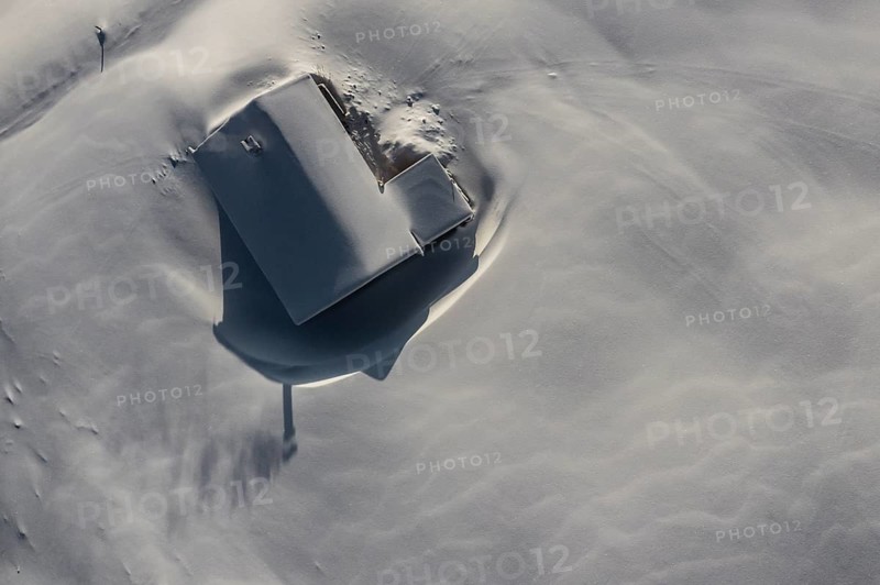 Snow-covered mountain hut in winter from above