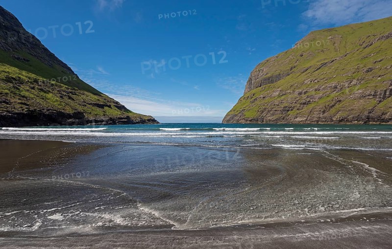 Sandy beach beach in bay surrounded by steep mountains
