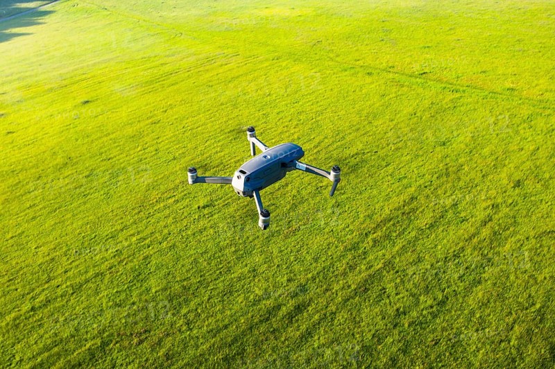 Flying drone DJI Mavic 2 Pro from above over meadow