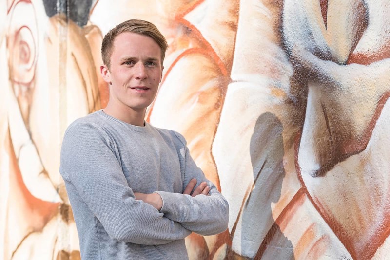 Young man in front of graffiti wall