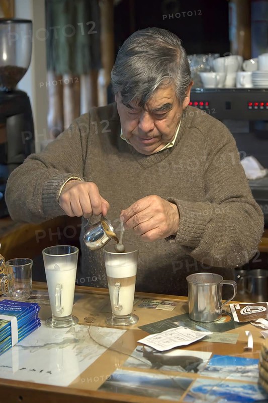 Shopkeeper brewing and serving cappuccino