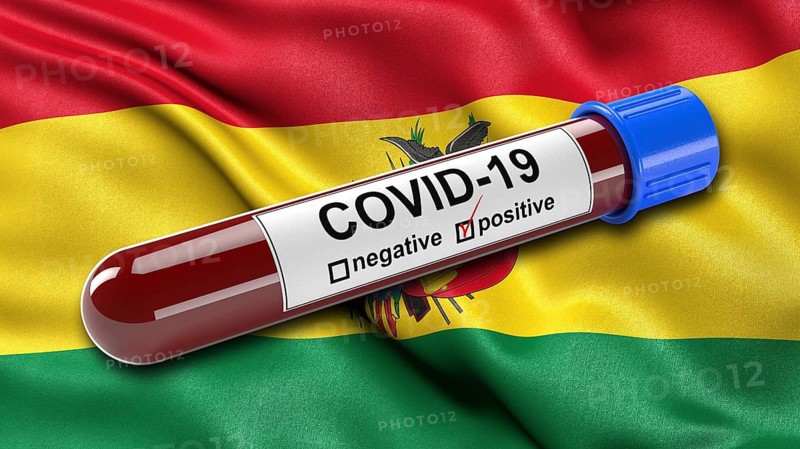 Flag of Bolivia waving in the wind with a positive Covid-19 blood tube