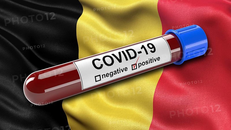 Flag of Belgium waving in the wind with a positive Covid-19 blood tube