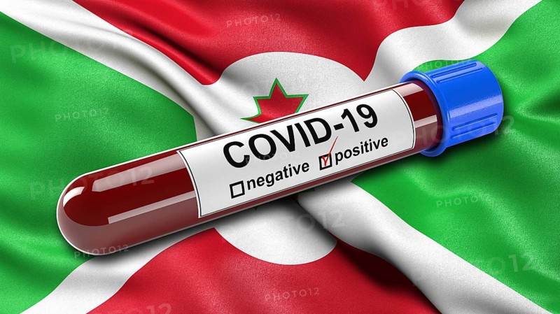 Flag of Burundi waving in the wind with a positive Covid-19 blood tube