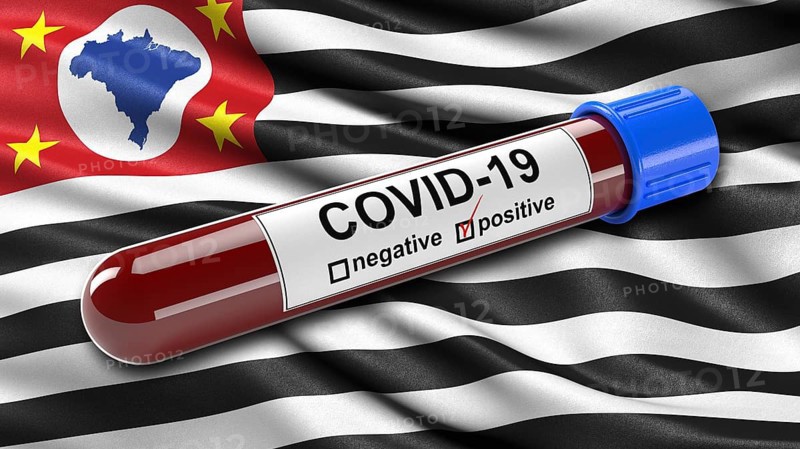 Flag of Sao Paulo waving in the wind with a positive Covid-19 blood tube