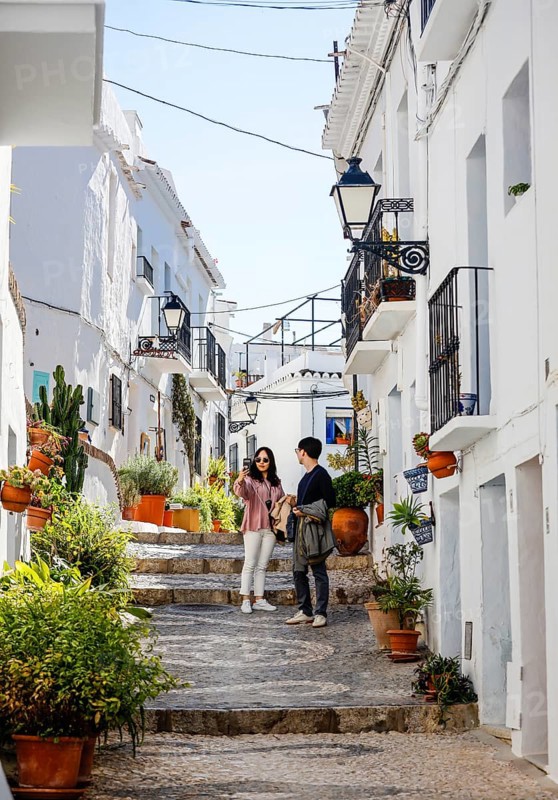 Asian tourists take pictures of themselves in picturesque alleys in the white mountain village of Frigiliana