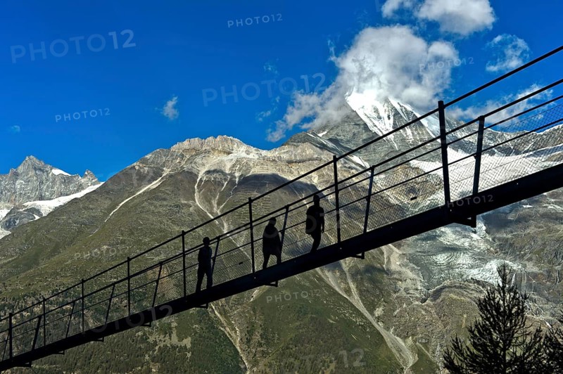 Hikers in the back light on the Charles Kuonen suspension bridge
