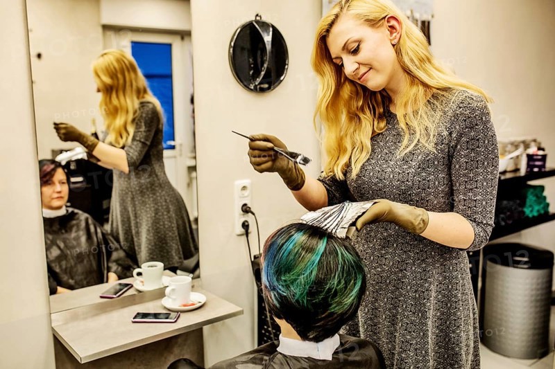 Hairdresser in a hairdressing salon dying strands of hair with aluminium foil