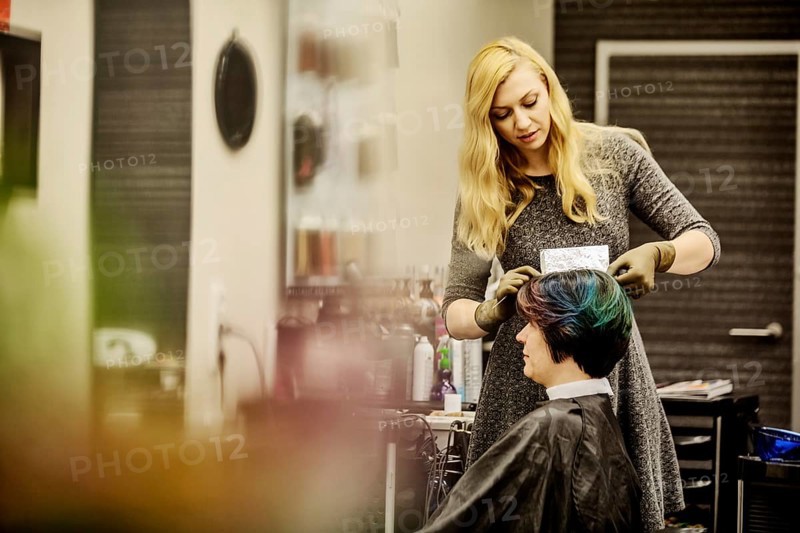 Hairdresser in a hairdressing salon dying strands of hair with aluminium foil