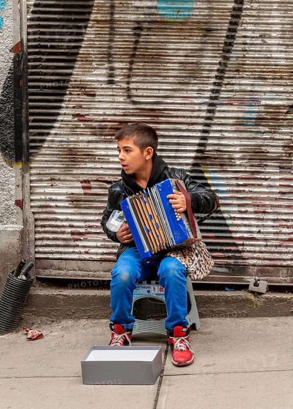 A boy playing the accordion on the road
