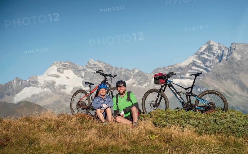Mountain biker couple sitting next to eBikes in the autumnal mountain scenery of the Stubaier Alps