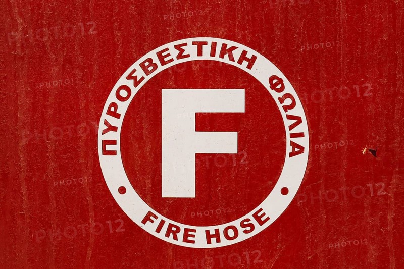 Close-up of red and white painted metal cabinet cover with Fire Hose written in Greek and English languages