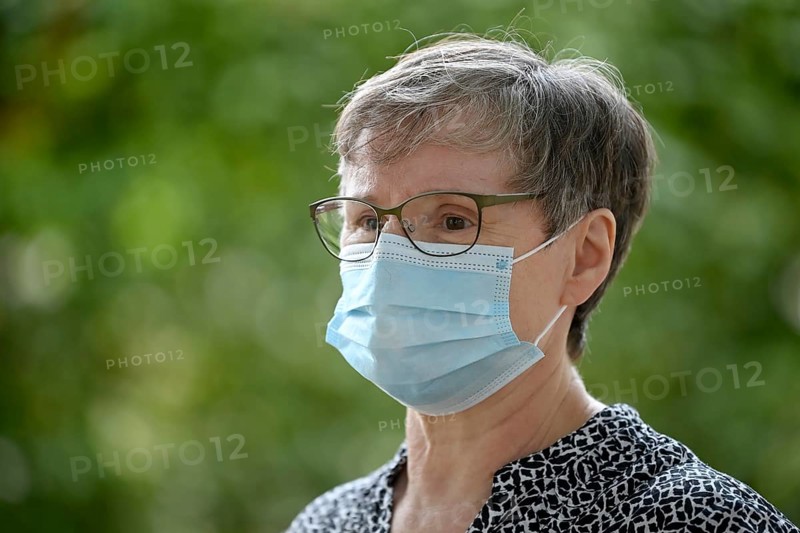 Elderly woman wears mouth mask correctly over nose and mouth