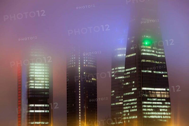 Cuatro Torres Business Area Office building illuminated in evening fog