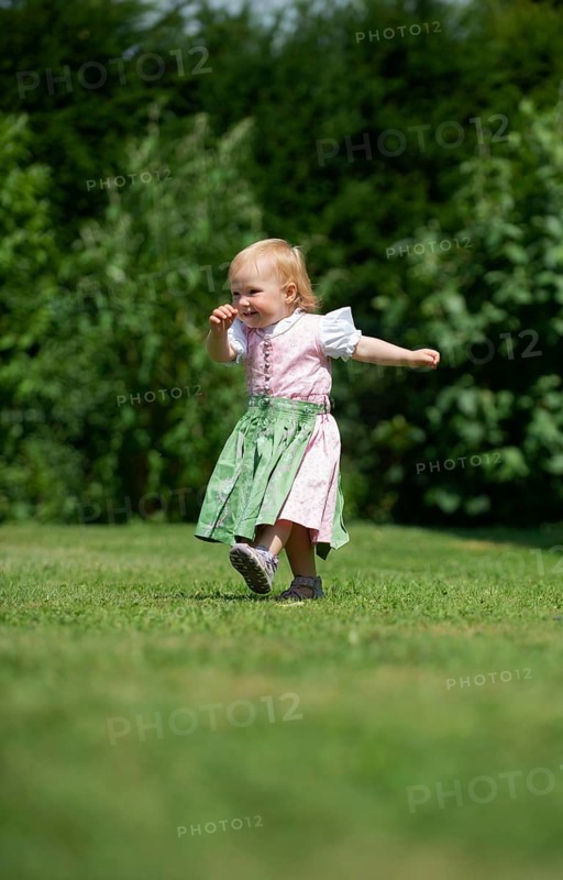 Girl in Dirndl runs across a meadow