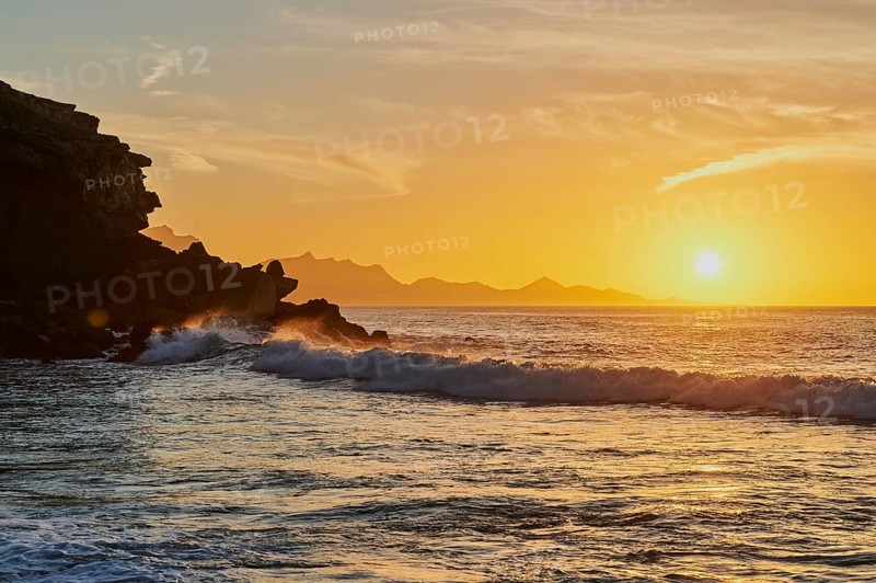 Beach Playa de la Pared with rocky coast at sunset