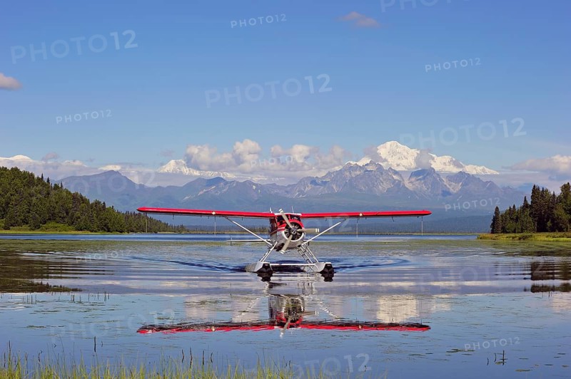 Seaplane Beaver de Havilland lands on a lake off snow-covered mountain Denali