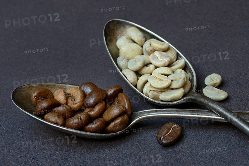 Green coffee and roasted coffee beans in spoon