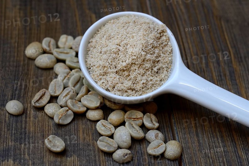 Green coffee beans and unroasted coffee powder in spoon