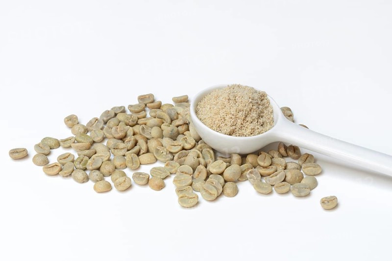 Green coffee beans and unroasted coffee powder in spoon