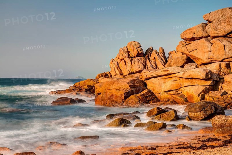 Red granite rocks and rough sea