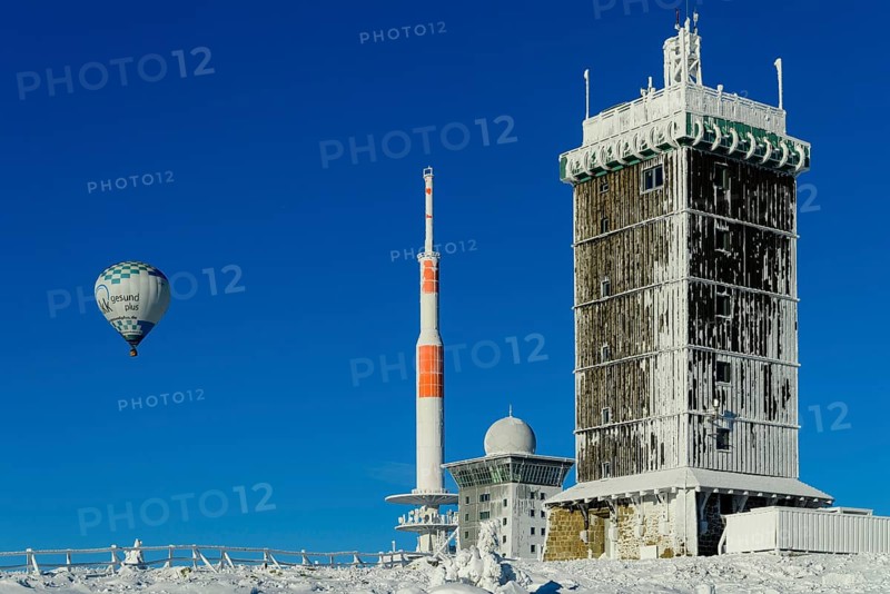 Hot-air balloon with transmitter mast and Brocken hostel on the winter snow-covered Brocken
