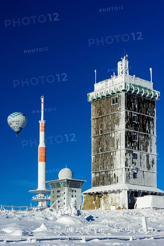 Hot-air balloon with transmitter mast and Brocken hostel on the winter snow-covered Brocken