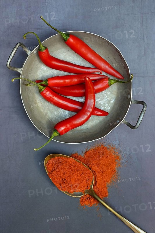 Chilli powder in spoon and chilli peppers in shell