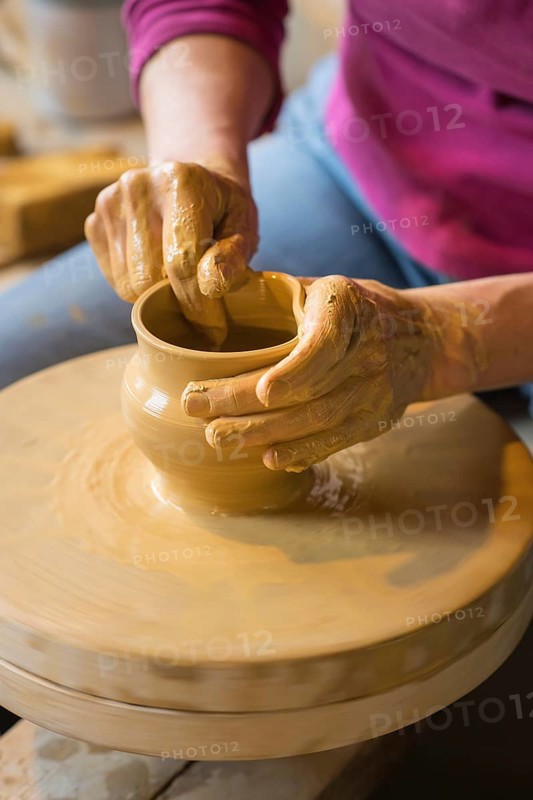 Potter turning a vase with her hands on the potter's pane