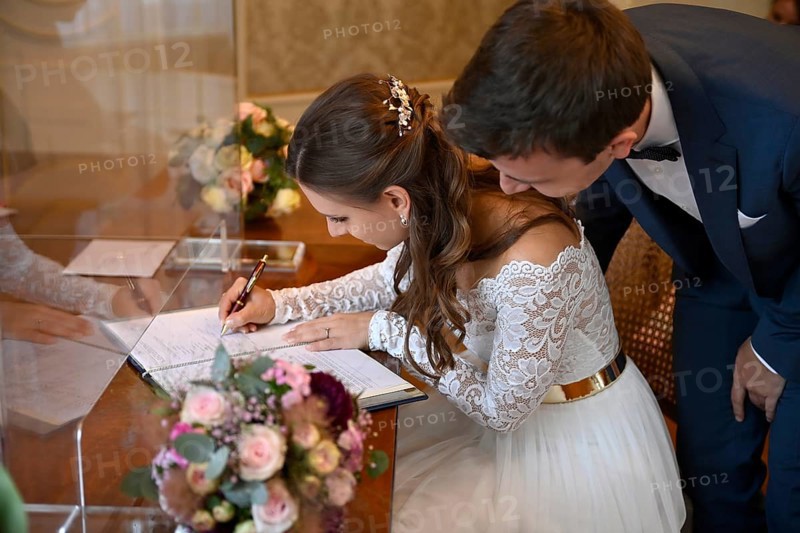 Bridal couple signs marriage certificate at the registry office