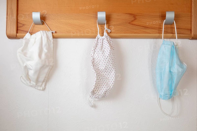 Various corona protection masks hang on coat hooks