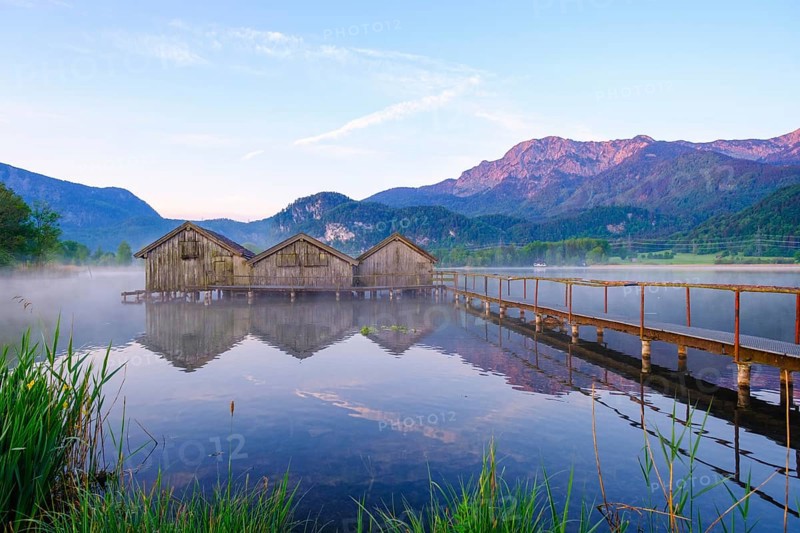 Boathouses and jetty in Lake Kochel near Schlehdorf in the morning light